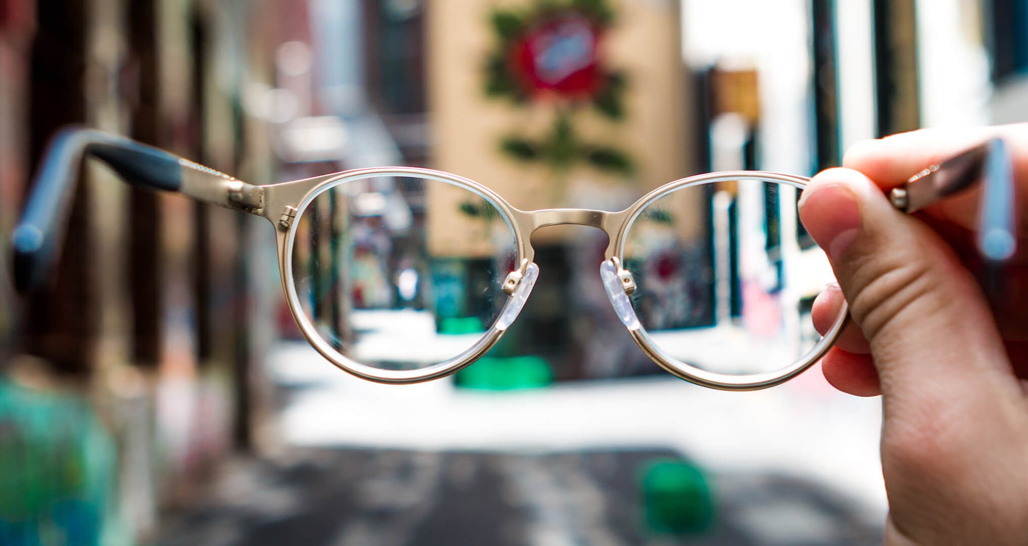 Person holding glasses out showing blurred city image