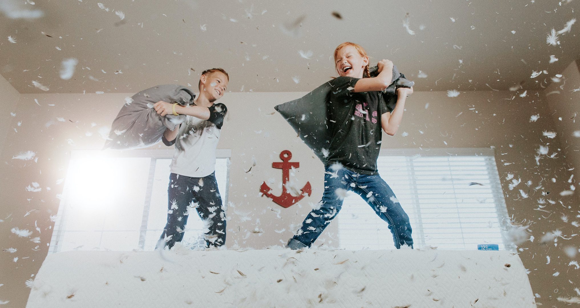 2 kids in pillow fight on bed